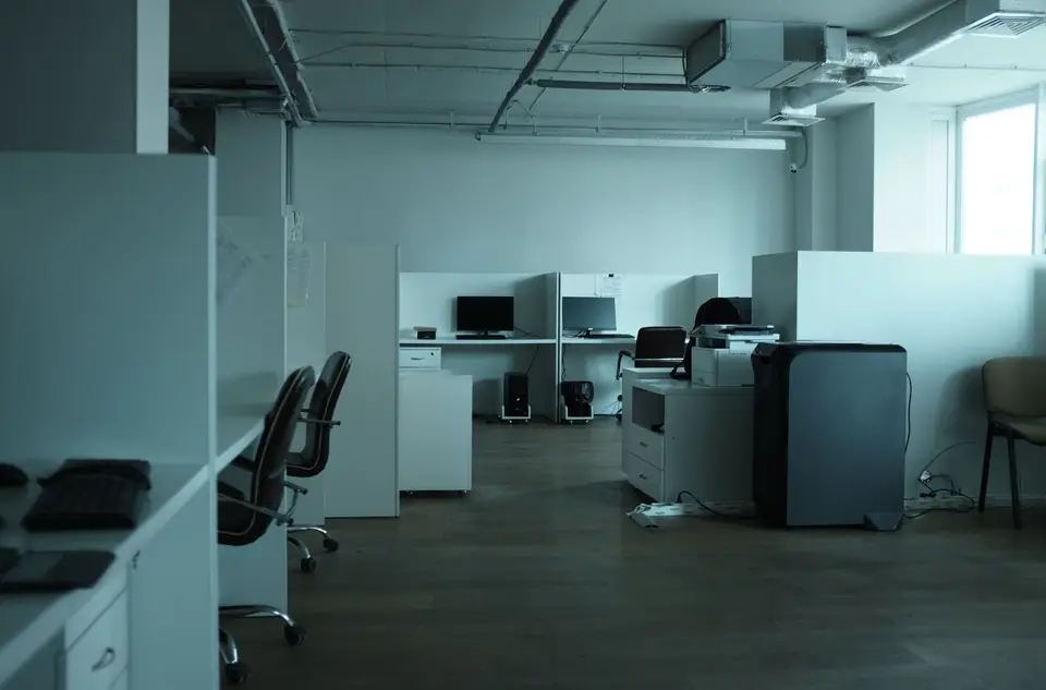 An empty modern office with desks, chairs and large windows.